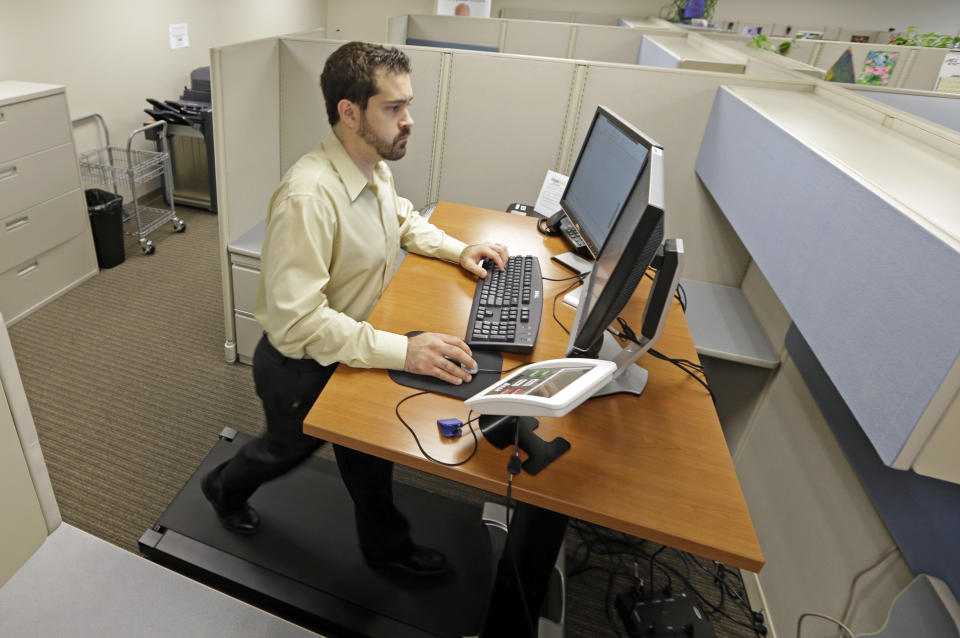 Josh Baldonado, an administrative assistant at Brown & Brown Insurance, works at a treadmill desk in the firms offices in Carmel, Ind., Wednesday, Aug. 28, 2013. Workers sign up for 30 slots not he treadmills and have their phone and computer transferred to the workstations. Being glued to your desk is no longer an excuse for not having time to exercise as a growing number of Americans are standing, walking and even cycling their way through the work day at treadmill desks, standup desks or other moving work stations. (AP Photo/Michael Conroy)