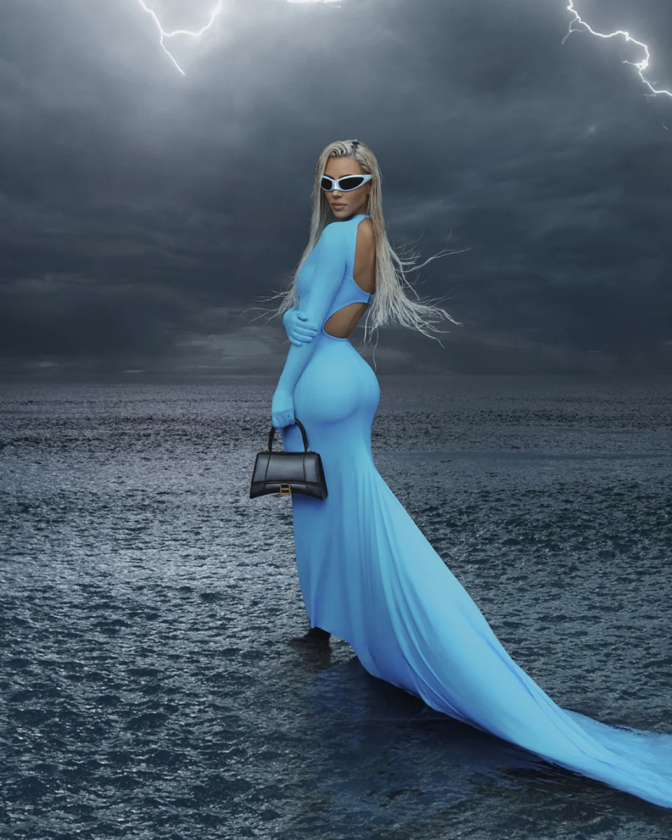 Kim Kardashian in a blue evening dress with lighting striking in background for a Balenciaga campaign.