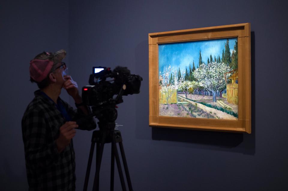 A man films a painting by Vincent Van Gogh entitled 'Orchard Bordered by Cypresses' during the exhibition 'Van Gogh in Provence: Modernizing Tradition' at the Fondation Vincent Van Gogh Arles on May 13, 2016 in Arles, southern France.