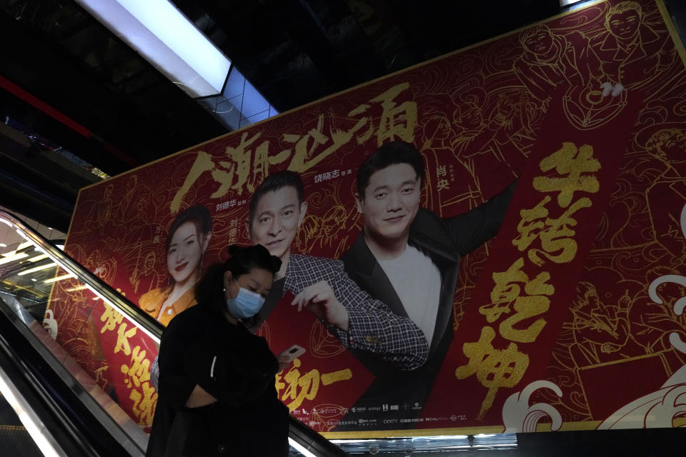 A woman wearing a mask passes by an ad for a movie in Beijing Thursday, Feb. 25, 2021. The state of the world's second largest economy takes precedence among the myriad issues presented by Premier Li Keqiang in his address at the National People's Congress opening session to take place on Friday, March 5. 2021. (AP Photo/Ng Han Guan)