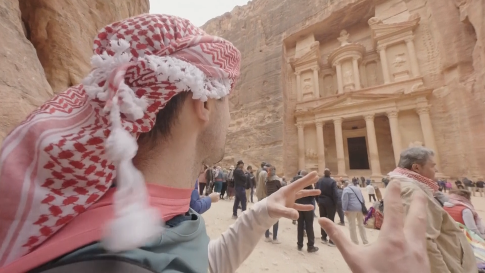 A still image of Jamie McDonald posing in front of Petra in Jordan grabbed from video. Petra is half-built, half-carved into the rock, and is surrounded by mountains riddled with passages and gorges, according to the World Heritage Convention.