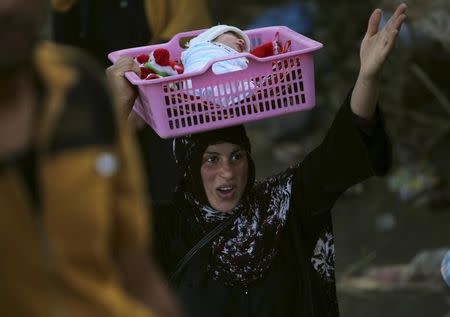 An Iraqi Sunni displaced woman, who fled the violence in the city of Ramadi carries her child on the outskirts of Baghdad, Iraq May 19, 2015. REUTERS/Stringer