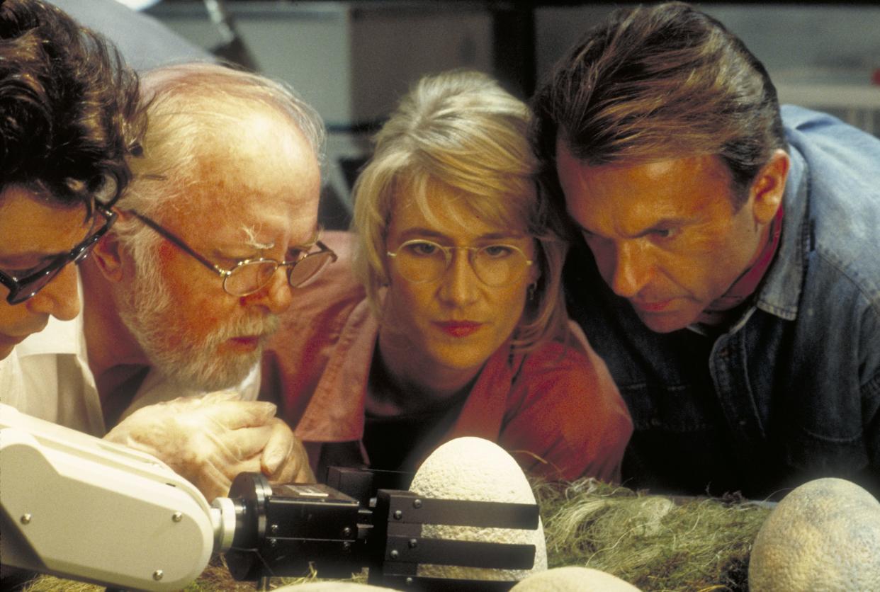 Jeff Goldblum as Dr. Ian Malcolm, Richard Attenborough as John Hammond, Laura Dern as Dr. Ellie Sattler and Sam Neill as Dr. Alan Grant, watching a robotic arm handle the dinosaur eggs in the film Jurassic Park.