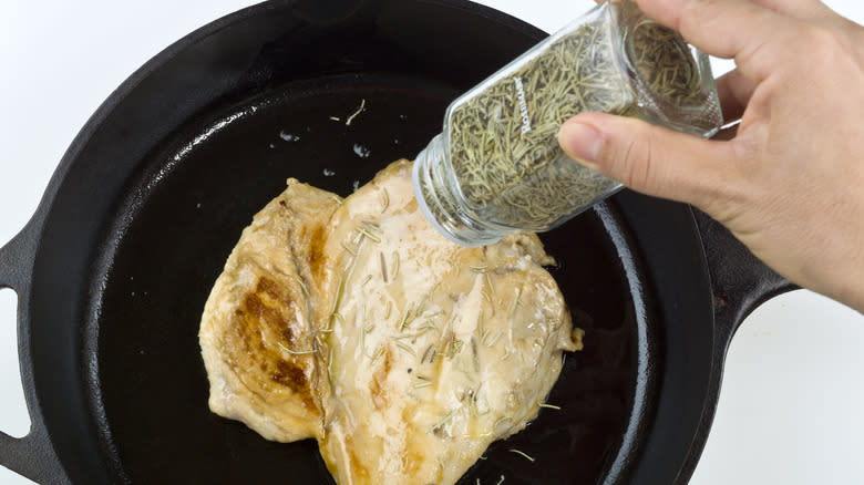 Shaking dried herbs into a pan