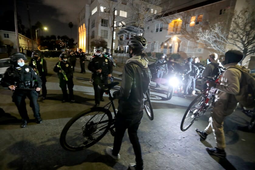 LOS ANGELES, CA - MARCH 25, 2021. Police officers and p[rotesters face off near a homeless camp in Echo Park that was closed on Thursday, Mar. 25, 2021. Dozens of homeless people lived at the park, but the number had dwindled to about a dozen after authorities told camp residents they had 24 hours to leave. (Luis Sinco / Los Angeles Times)