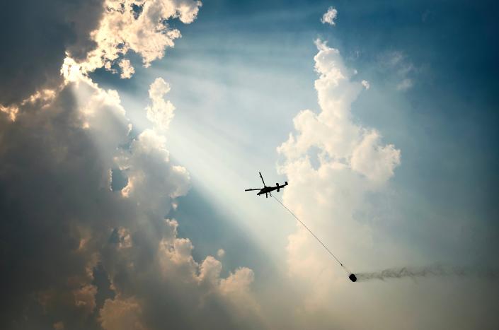 A helicopter carries a water bucket while battling the McKinney Fire on Tuesday in the Klamath National Forest in western Siskiyou County.