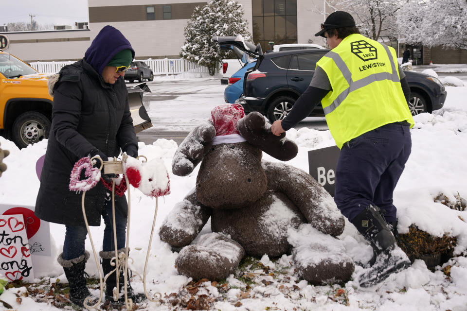 A large stuffed moose is cleared of snow before being packed away, Tuesday, Dec. 5, 2023, at one of the several memorials for the victims of last month's mass shooting in Lewiston, Maine. Officials began removing memorials to the 18 people killed. The items will be cataloged, archived and displayed in a museum. (AP Photo/Robert F. Bukaty)