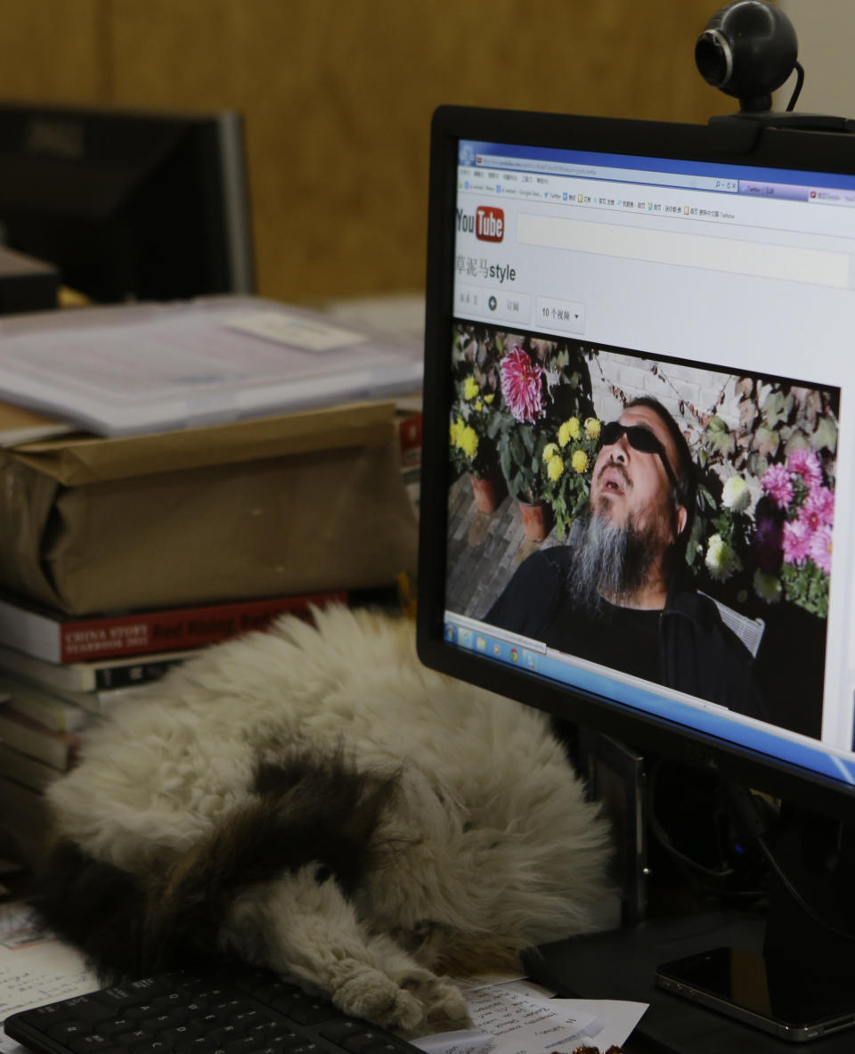 Chinese dissident artist Ai Weiwei appears on a YouTube video clip displayed on a computer screen at his studio in Beijing, China, Thursday, Oct. 25, 2012. In the video, Ai sports a neon-pink T-shirt, black jacket and dark sunglasses and energetically mimics rodeo-style dance moves made famous by South Korean rapper PSY whose original video became an Internet sensation. (AP Photo/Ng Han Guan)