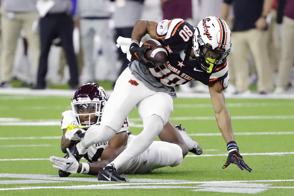 Oklahoma State wide receiver Brennan Presley slips past the tackle attempt by Texas A&M defensive back Jayvon Thomas during the first half of the Texas Bowl NCAA college football game Wednesday, Dec. 27, 2023, in Houston. (AP Photo/Michael Wyke)