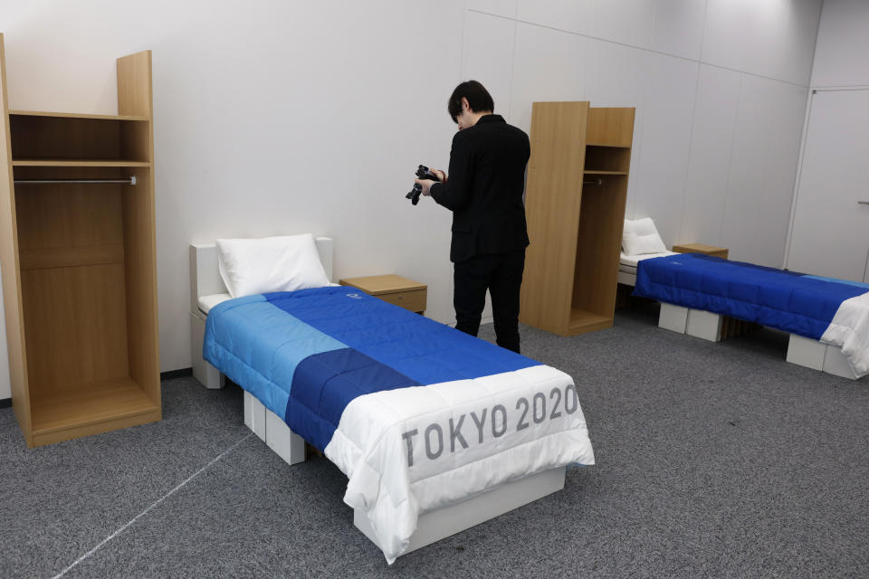 A journalist films a cardboard bed in a display room showing furniture for the Tokyo 2020 Olympic and Paralympic Villages Thursday, Jan. 9, 2020, in Tokyo. Tokyo Olympic athletes beware - particularly larger ones. The single bed frames in the Athletes Village at this year's Olympics will be made of cardboard. The single bed frames will be recycled into paper products after the games. The mattress components - the mattress are not made of cardboard - will be recycled into plastic products.. (AP Photo/Jae C. Hong)