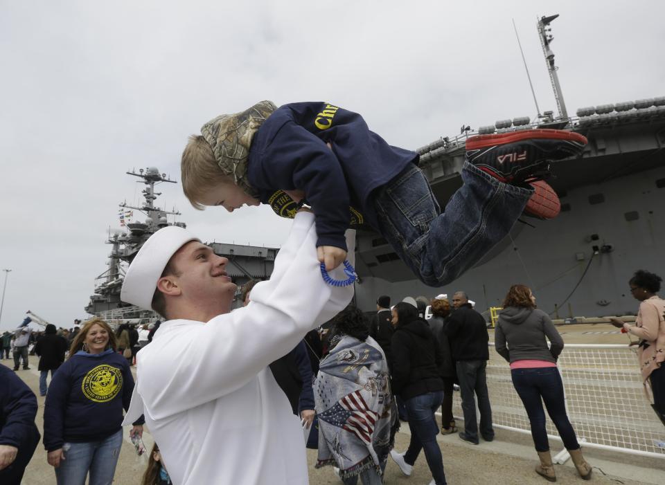 Kollia Safford, from Delhi N.Y., is lifted by his godfather, Communications Specialist, Christopher Payne, after he disembarked from the nuclear aircraft carrier Harry S. Truman at Naval Station Norfolk in Norfolk, Va., Friday, April 18, 2014. The Truman Strike Group arrive after a 9-month deployment to the Middle East. (AP Photo/Steve Helber)