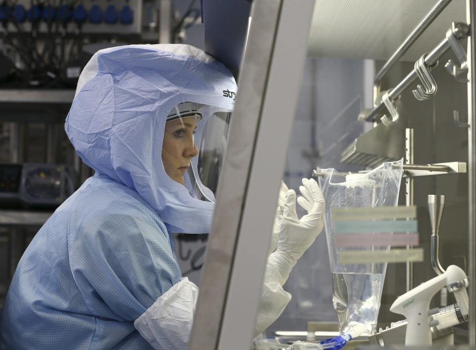 A scientist in a biohazard suit makes a vaccine in the lab