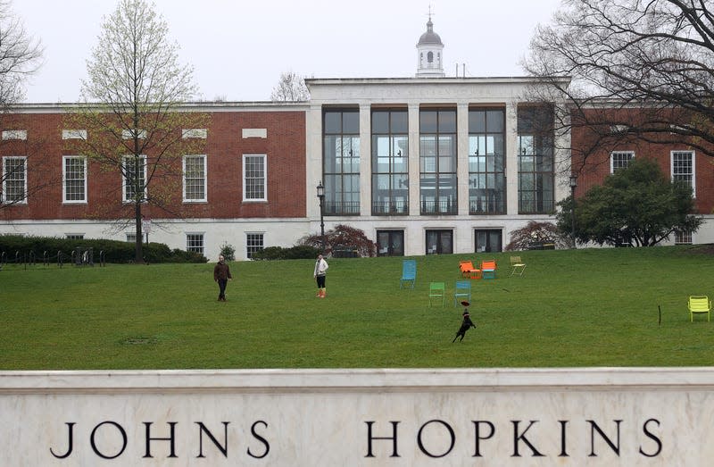 Two people and a dog on a lawn on Johns Hopkins campus.