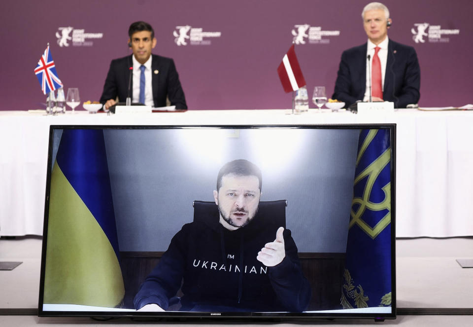 Ukrainian President Volodymyr Zelenskyy speaks via video link as Latvian Prime Minister Krisjanis Karins and British Prime Minister Rishi Sunak listen, during the Joint Expeditionary Force (JEF) meeting in Riga, Latvia, Monday, Dec. 19, 2022. As milestones go, the first anniversary of Russia's invasion of Ukraine is both grim and vexing. It marks a full year of killing, destruction, loss and pain felt even beyond the borders of Russia and Ukraine. (Henry Nicholls/Pool Photo via AP)