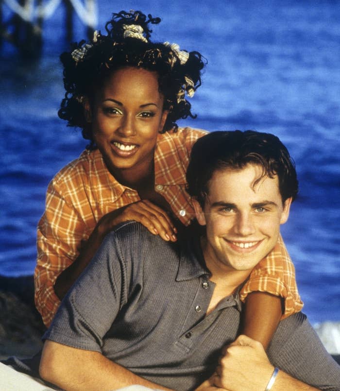 Trina McGee in a checkered shirt smiles while resting her arms on Rider Strong's shoulders