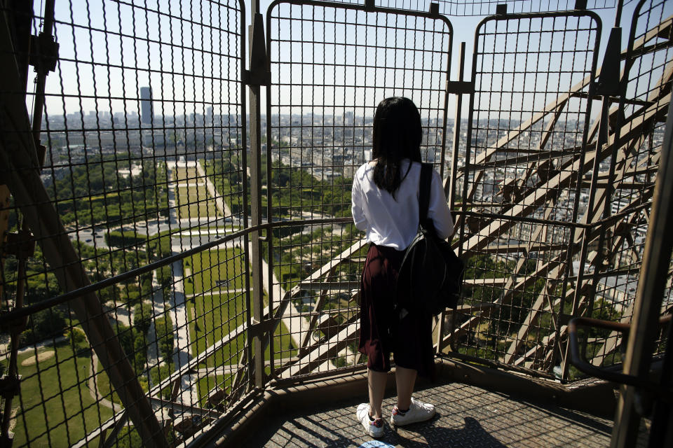 A visitor enjoys the view as she climbs the stairs of the Eiffel Tower, in Paris, Thursday, June 25, 2020. The Eiffel Tower reopens after the coronavirus pandemic led to the iconic Paris landmark's longest closure since World War II. (AP Photo/Thibault Camus)