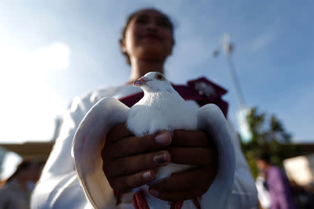 A girls holds a pigeon during a ceremony to mark the 39th anniversary of the toppling of Pol Pot's Khmer Rouge regime, in Phnom Penh, Cambodia, January 7, 2018. REUTERS/Samrang Pring