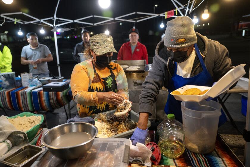 FONTANA, CA - DECEMBER 15, 2023: Food vendors Angelina Matias and her husband Librado Castillo of Fontana make homemade pupusas at their food stand off Sierra Avenue on December 15, 2023 in Fontana, California. Recently, she had all her food tossed and equipment confiscated by code enforcement. The city of Fontana just passed an ordinance contracting a third-party company for $600,000 to patrol and impound street vendors' equipment that lack the required permit.(Gina Ferazzi / Los Angeles Times)