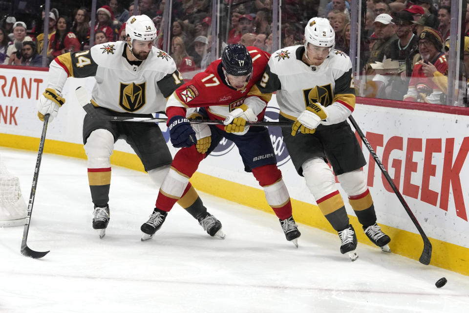 Vegas Golden Knights defenseman Nicolas Hague (14), Florida Panthers center Evan Rodrigues (17) and Golden Knights defenseman Zach Whitecloud (2) chase the puck during the second period of an NHL hockey game, Saturday, Dec. 23, 2023, in Sunrise, Fla. (AP Photo/Lynne Sladky)