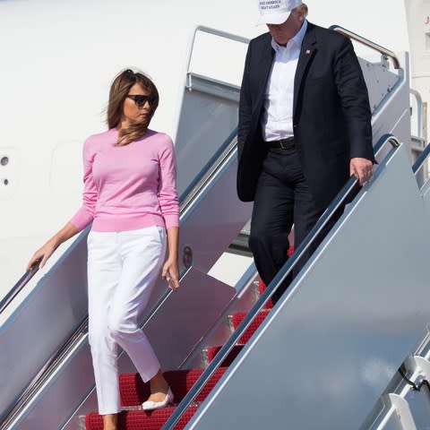 Melania Trump exits Air Force One in a crisp white chino and candy pink sweater.  - Credit: Saul Loebsaul. /Getty. 