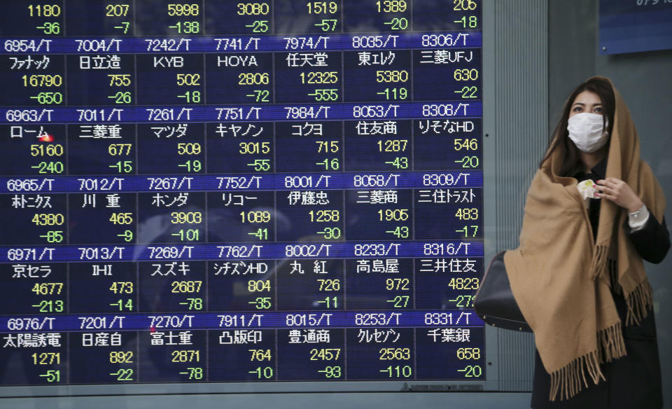 A woman takes shelter from the rain by an electronic stock board of a securities firm in Tokyo Thursday, Jan. 30, 2014. Shares fell Thursday in Asia as weak economic data from China and Japan deepened concerns over ongoing reductions in U.S. monetary stimulus. Japan's Nikkei 225 index was down 2.6 percent at 14,887.96 after the government reported that retail sales fell 1.1 percent in December from the month before. It gained slightly and closed at 15,007.06 for the day. (AP Photo/Koji Sasahara)