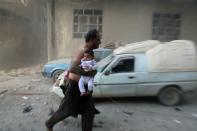 Un homme avec un bébé s'enfuit après des bombardements sur Kafr Batna, dans la banlieue de Damas, le 30 septembre 2016