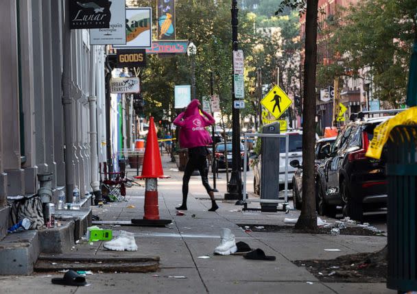 PHOTO: A woman looks for her shoes that were left at scene of a mass shooting is cordoned off by law enforcement in Over-the-Rhine, Cincinnati, Aug. 7, 2022. (Liz Dufour/Cincinnati Enquirer via USA Today Network)