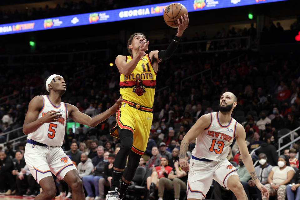 Atlanta Hawks guard Trae Young (11) goes up for a lay up as New York Knicks guard Immanuel Quickley (5) and guard Evan Fournier (13) defends during the first half of an NBA basketball game Saturday, Jan. 15, 2022, in Atlanta. (AP Photo/Butch Dill)