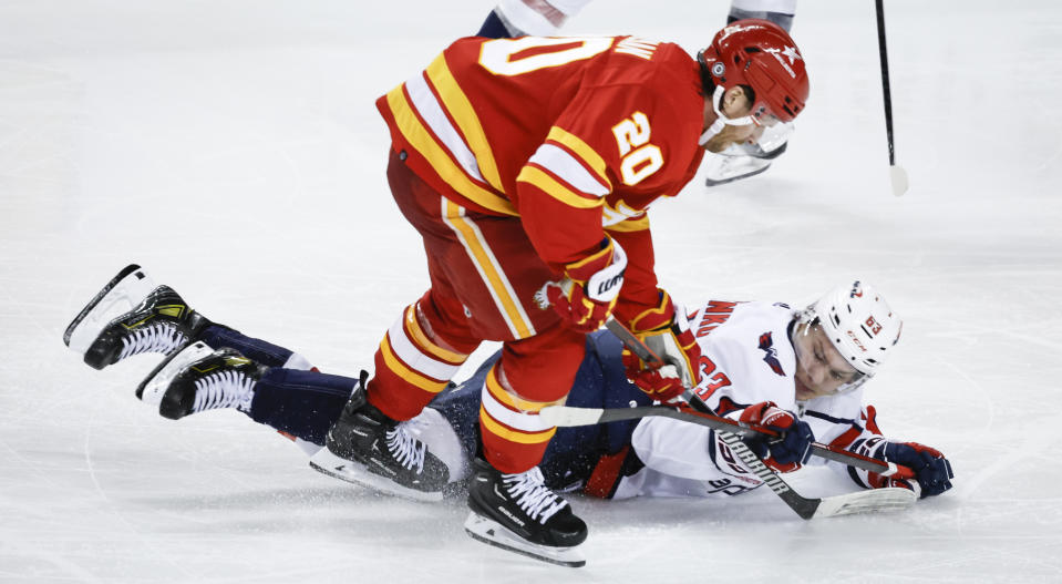 Washington Capitals forward Ivan Miroshnichenko (63) is checked by Calgary Flames forward Blake Coleman (20) during the third period of an NHL hockey game in Calgary, Alberta, Monday, March 18, 2024. (Jeff McIntosh/The Canadian Press via AP)