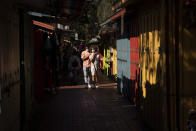 Alexia Thorpe and her boyfriend, Bennett Olupo are lit by afternoon sunlight as they stroll past stalls lining along Olvera Street in Los Angeles, Friday, June 4, 2021. Most businesses are no longer open daily and many have cut back to four or five days, said Valerie Hanley, treasurer of the Olvera Street Merchants Association Foundation and a shop owner. "We're not like a local restaurant in your town," Hanley said. "We're one of those little niche things. If you can't fill the niche with the right people, we're in trouble." (AP Photo/Jae C. Hong)