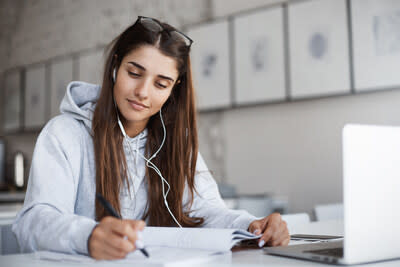 Female student at desk in front of a laptop writing notes. (CNW Group/Studiosity)