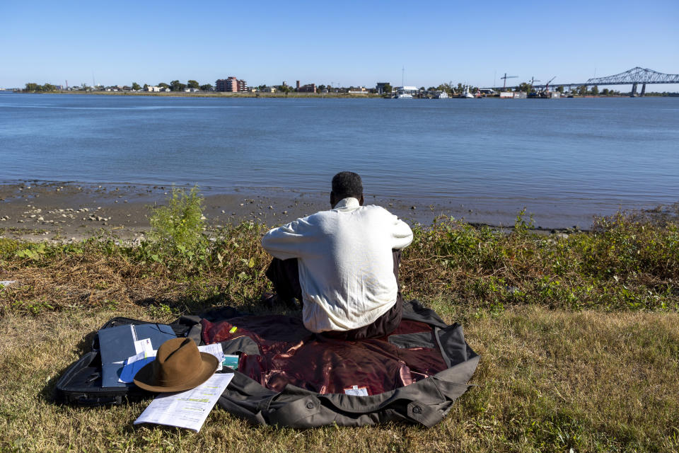 A man sits along Woldenberg Park by the Mississippi River in New Orleans on Oct. 19, 2022. Dry land, left, can be seen along the river. (Chris Granger/The Times-Picayune/The New Orleans Advocate via AP)