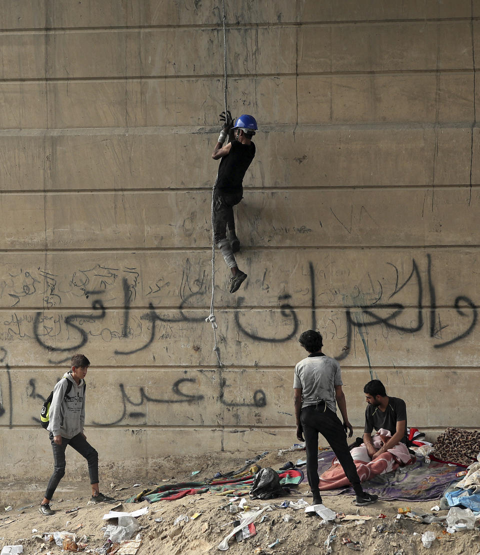 An anti-government protester climbs the Joumhouriya Bridge that leads to the Green Zone government area, during ongoing protests in Baghdad, Iraq, Sunday, Nov. 3, 2019. Arabic reads, “Iraq is Iraqi.” (AP Photo/Hadi Mizban)