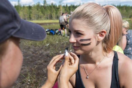 Players of SuoSiat get a war paint on their faces before the game at the Swamp Soccer World Championships tournament in Hyrynsalmi, Finland July 13, 2018. Picture taken July 13, 2018. Lehtikuva/Kimmo Rauatmaa/via REUTERS