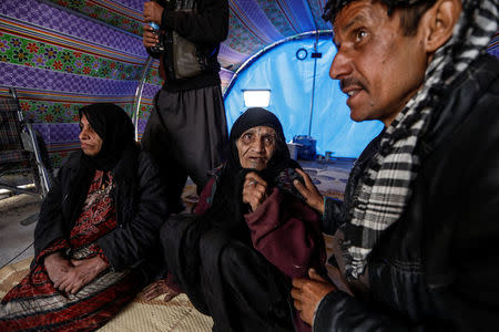 Khatla Ali Abdullah, 90, who recently fled her home in Al Mamoun district talks to her relative as she sits with her daughter (L) in her tent in Hammam al Alil camp, while Iraqi forces battle with Islamic State militants, in western Mosul, Iraq March 1, 2017. REUTERS/Zohra Bensemra