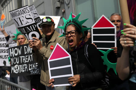 Protesters hold signs near the Intrepid Sea, Air & Space Museum ahead of an expected visit by U.S. President Donald Trump in the Manhattan borough of New York City, U.S., May 4, 2017. REUTERS/Shannon Stapleton