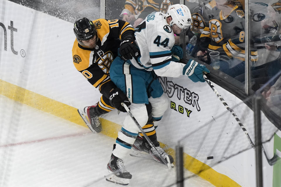 Boston Bruins left wing A.J. Greer (10) vies for control of the puck with San Jose Sharks defenseman Marc-Edouard Vlasic (44) as they crash into the boards in the first period of an NHL hockey game, Sunday, Jan. 22, 2023, in Boston. (AP Photo/Steven Senne)