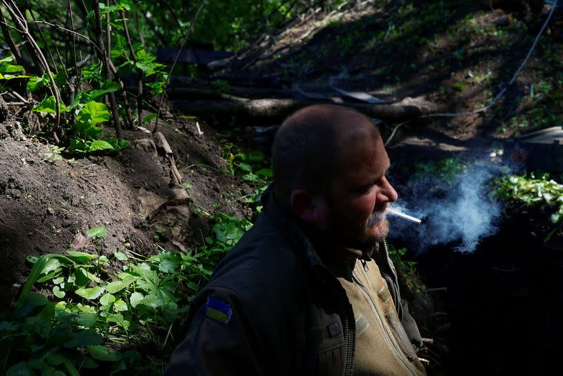 FILE PHOTO: Ukrainian serviceman Hryhorii smokes next to a dugout at a position near a front line in Donetsk region