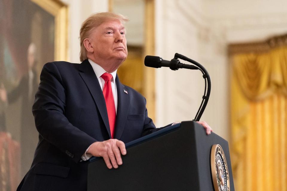 Former President Donald Trump standing before a podium.