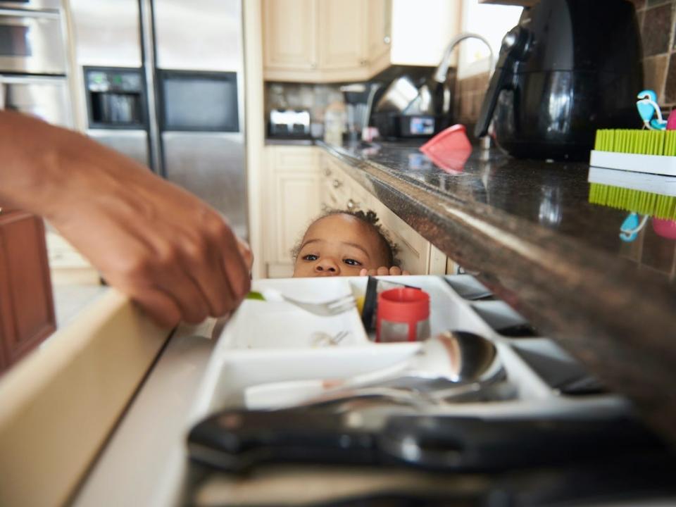 A child peers into a kitchen drawer.