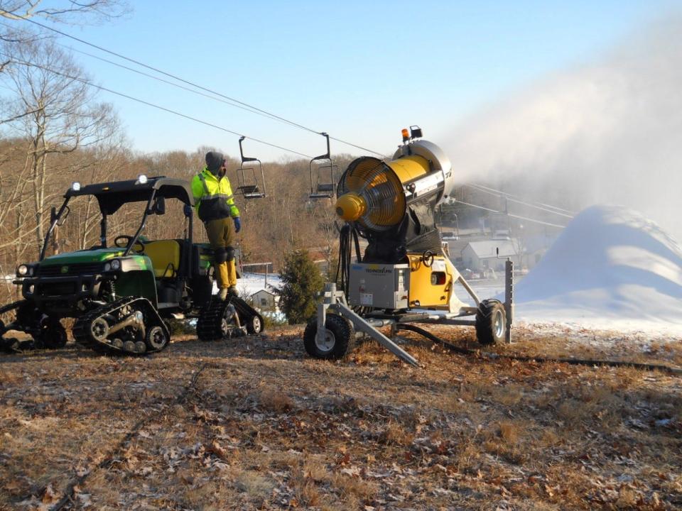 Surrounded by bare ground, a Yawgoo staffer monitors a snow-maker this winter.