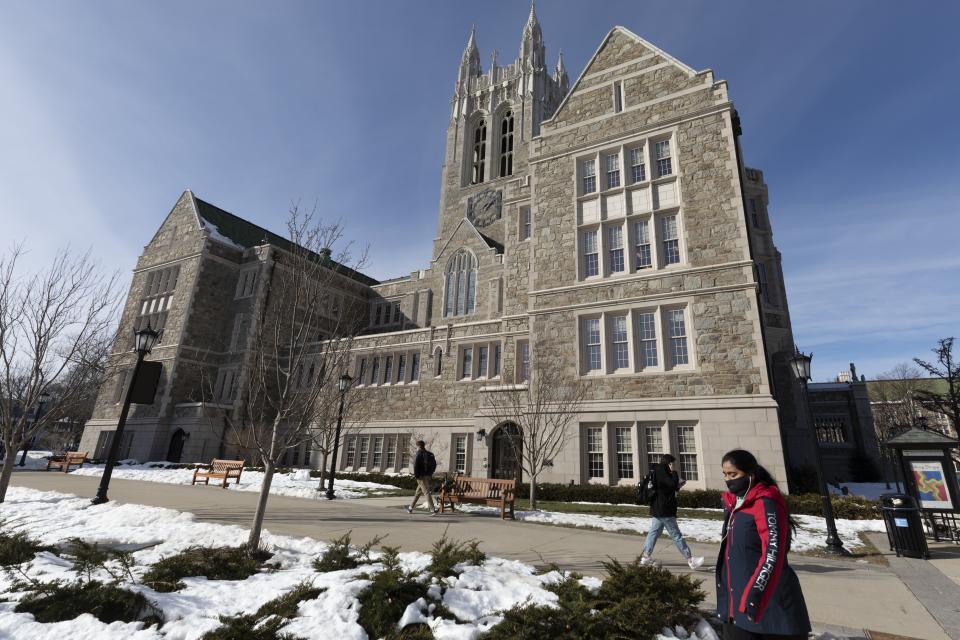 Students walk on the Boston College campus, Wednesday, Feb. 17, 2021, in Boston. (AP Photo/Michael Dwyer)