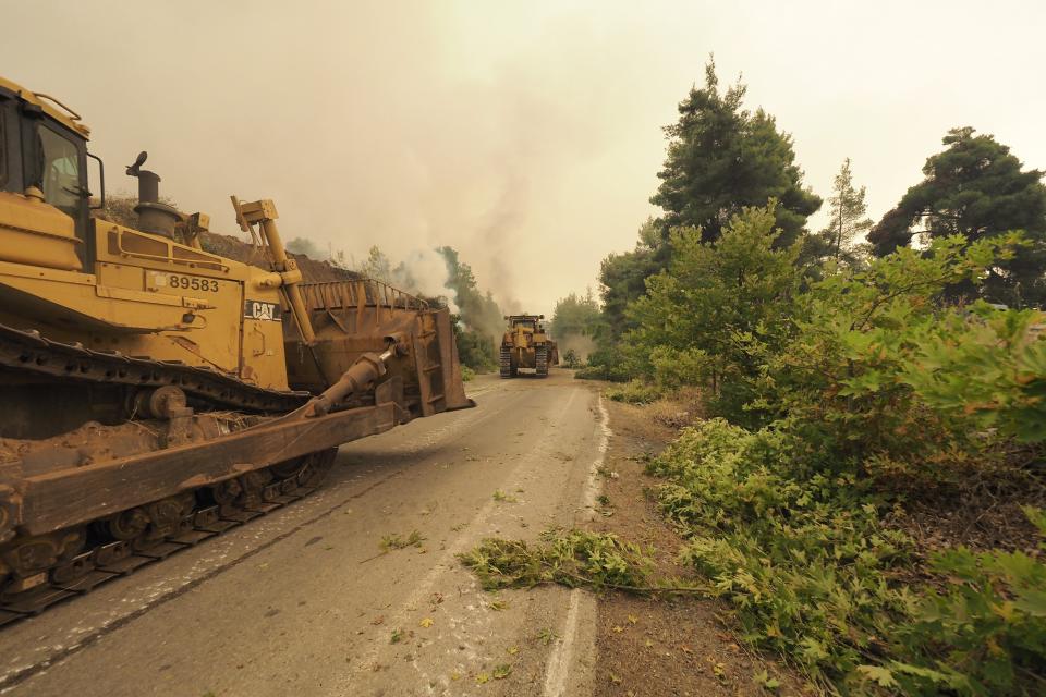 Bulldozers open fire break at a forest during a wildfire near Kechries village on the island of Evia, about 144 kilometers (90 miles) north of Athens, Greece, Thursday, Aug. 5, 2021. Forest fires fueled by a protracted heat wave raged overnight and into Thursday in Greece, threatening the archaeological site at the birthplace of the modern Olympics and forcing the evacuation of dozens of villages. (AP Photo/Thodoris Nikolaou)