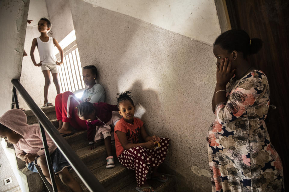 Nine month pregnant Eritrean asylum seeker Alganesh Fesahye sit with her children as they take shelter in the stairwell outside their apartment in Ashdod, Israel during a siren warning of rockets fired from Gaza Strip, Tuesday, May 18,2021. (AP Photo/Heidi Levine)