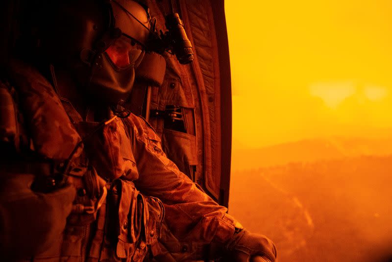 Warrant Officer Class Two Darrel Rowe, from the 5th Aviation Squadron, searches the ground from an Australian Army CH-47F Chinook during the flight to Omeo