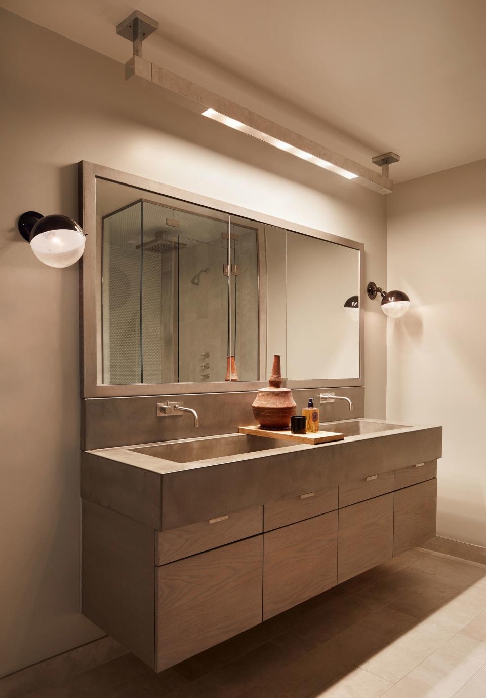 A vintage hanging light from John Salibello Antiques and a pair of Obsolete sconces illuminate a custom wood-and-concrete vanity.