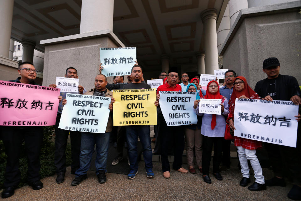 <p>Supporters of former Malaysian prime minister Najib Razak seen holding up signs, ahead of his arrival at the Kuala Lumpur Courts Complex on Wednesday (4 July) morning. (PHOTO: Reuters) </p>
