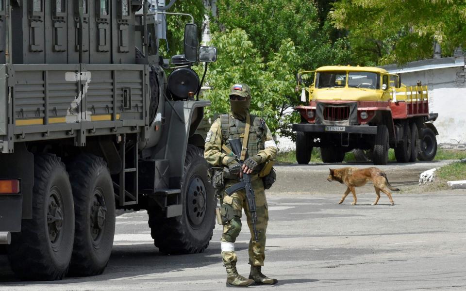 A Russian serviceman patrolling the street in Kherson - AFP