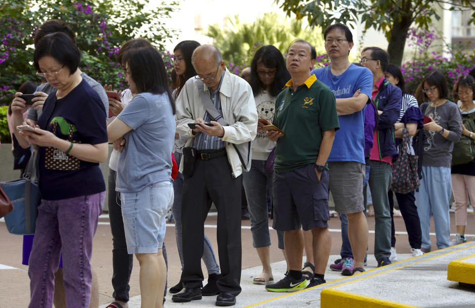 People line up to vote outside of a polling place in Hong Kong, Sunday, Nov. 24, 2019. Long lines formed outside Hong Kong polling stations Sunday in elections that have become a barometer of public support for anti-government protests now in their sixth month. (AP Photo/Vincent Yu)