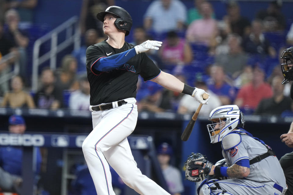 Miami Marlins' Garrett Cooper follows through on an RBI single to score Jazz Chisholm Jr. during the first inning of the team's baseball game against the New York Mets, Friday, June 24, 2022, in Miami. At right is Mets catcher Tomas Nido. (AP Photo/Lynne Sladky)